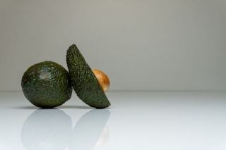 Avocat coupé en deux et son noyau Un avocat coupé en deux, son noyau visible, posé sur une planche en bois